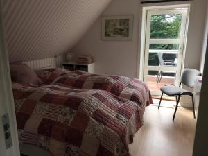 ein Schlafzimmer mit einem Bett, einem Fenster und einem Stuhl in der Unterkunft Nationalpark Thy guesthouse in Vestervig