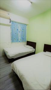 a room with two beds and a blue curtain at Fengchia Bichon B&B in Taichung