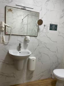 ein Badezimmer mit einem Waschbecken, einem Spiegel und einem WC in der Unterkunft Fortetsya in Chmelnyzkyj