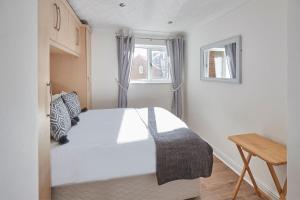 a bedroom with a white bed and a window at Apartment 2, Khyber Lodge Apartment Whitby in Whitby +3 photos