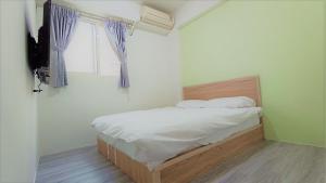 a bed in a room with a window at Fengchia Bichon B&B in Taichung