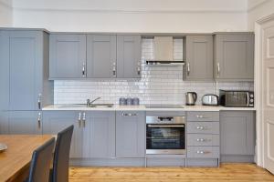 cocina con armarios grises y mesa de madera en Apartment 3, Khyber Lodge Apartments Whitby, en Whitby