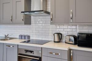 a kitchen with stainless steel appliances and white cabinets at Apartment 3, Khyber Lodge Apartments Whitby in Whitby