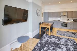 a kitchen with a table and a tv on a wall at Apartment 3, Khyber Lodge Apartments Whitby in Whitby