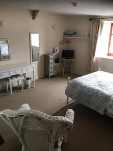 a bedroom with a bed and a desk and a mirror at The Malt Scoop Inn in Merton