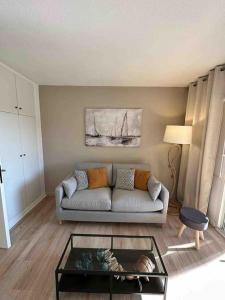 sala de estar con sofá y mesa de cristal en Appartement climatisé bord de plage et piscine, en Cogolin