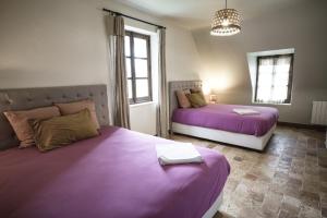 2 camas en una habitación con sábanas moradas en The Holy Farmhouse, en Fontaine-Simon