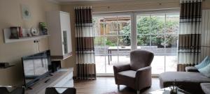 ein Wohnzimmer mit einem Sofa, einem Stuhl und einem TV in der Unterkunft Ferienwohnung Reddemann in Westerstede