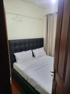 1 cama con cabecero negro y almohadas blancas en G&G Homes Ngala Nakuru, en Nakuru