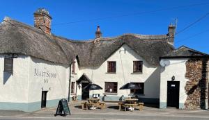 a white building with picnic tables in front of it at The Malt Scoop Inn in Merton