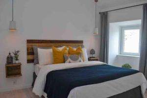 um quarto com uma cama grande com almofadas azuis e amarelas em Casa de férias Óbidos em Óbidos