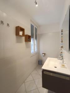 a white bathroom with a sink and a window at Blackstone Apartment in Varazze