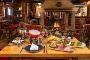 a table with food and wine glasses and a fireplace at MONDI Schiefe Alm Gastein in Bad Gastein