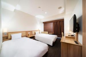 a hotel room with two beds and a flat screen tv at KOKO HOTEL Sapporo Ekimae in Sapporo