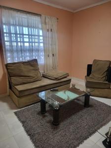 - un salon avec un canapé et une table en verre dans l'établissement G&G Homes Naka Nakuru, à Nakuru
