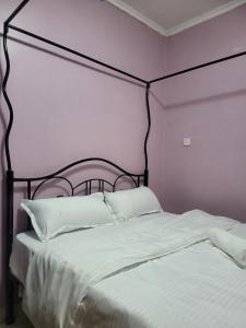a bed with a black frame and white sheets and pillows at G&G Homes Naka Nakuru in Nakuru