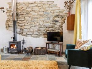Two Shoes Cottage في أوكهامبتون: غرفة معيشة مع جدار حجري ومدفأة