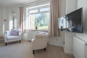 uma sala de estar com uma televisão, uma cadeira e uma janela em Ledgowan Lodge Hotel em Achnasheen