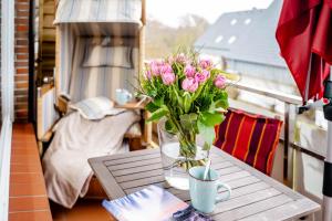 un jarrón de flores rosas sobre una mesa en un balcón en Auszeit im Austernfischer en Wenningstedt