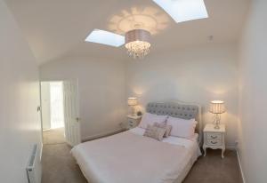 a bedroom with a white bed and a chandelier at Ledgowan Lodge Hotel in Achnasheen