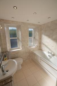 a bathroom with a tub and a toilet and a sink at Ledgowan Lodge Hotel in Achnasheen