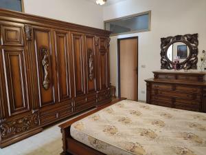 1 dormitorio con cama de madera y espejo en Campolo Apartment, en Reggio Calabria