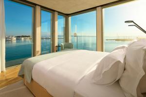 a bedroom with a large white bed and large windows at Hotel Ambasador in Split