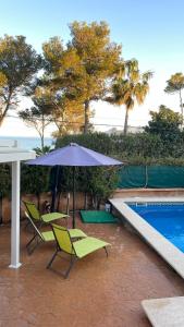 a patio with chairs and an umbrella next to a pool at Casa Xisca in Cala Pi