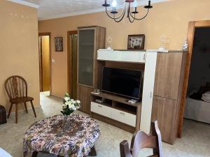 ein Wohnzimmer mit einem Fernseher und einem Tisch mit Blumen darauf in der Unterkunft Playas Rihuete 7 in Puerto de Mazarrón + 7 Fotos