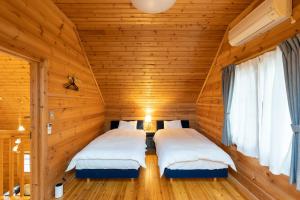 - 2 lits dans une chambre dotée de murs en bois dans l'établissement スイートヴィラ那須高原ログMoiMoi, à Nasu