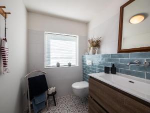 a bathroom with a sink and a toilet and a mirror at B&B De Oude Skuur in Oosterend