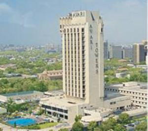 卡拉奇Avari Towers Karachi的一座高大的白色建筑，前面有一个游泳池