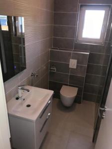 ein Bad mit einem Waschbecken, einem WC und einem Fenster in der Unterkunft Apartments Delfin - sea view in Prvić Šepurine