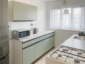 een keuken met een magnetron en een fornuis top oven bij 3 Bedroom flat in Hockley Birmingham near city centre, comfy and convenient in Birmingham