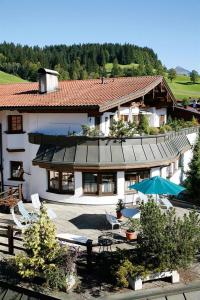 a large white house with chairs and an umbrella at Ferienwohnung Kober in Hopfgarten im Brixental