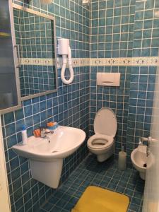 uma casa de banho em azulejos azuis com um WC e um lavatório em Attico sul Porto Vecchio - Lampedusa em Lampedusa