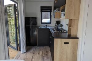 uma cozinha com um frigorífico preto e um lavatório em Mobil-home Camping Biscarosse em Biscarrosse