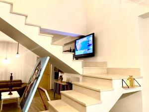 a living room with stairs with a tv on the wall at The Golden Palm - City Retreat in Aci Castello