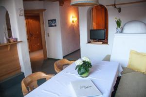 a white table with a vase of flowers on it at Ferienwohnung Kober in Hopfgarten im Brixental