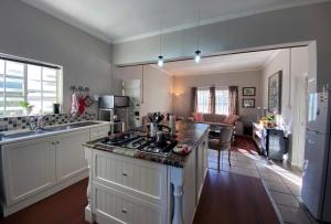 a kitchen with a stove top oven next to a living room at Olive and Vine Farm Cottage in Franschhoek
