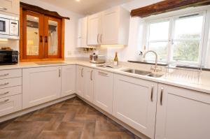 a kitchen with white cabinets and a sink at Barn End in Elterwater