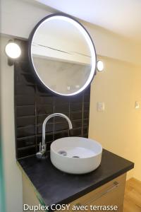 a bathroom sink with a large mirror on the wall at Duplex cosy avec terrasse in Marseille