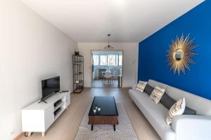 a living room with a couch and a blue wall at Le Mans Est - Idéal Pro & Groupe - 8 maxi - Wifi in Allonnes