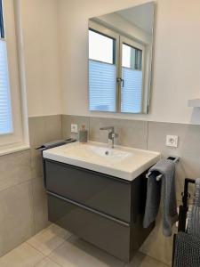 ein Bad mit einem Waschbecken und einem Spiegel in der Unterkunft Moderne Wohnung in Heskem bei Marburg (Lahn) 