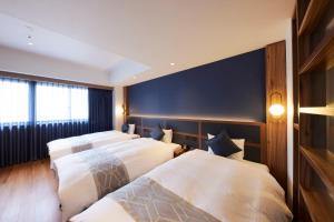 a row of four beds in a hotel room at HOTEL SAILS in Osaka