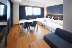 大阪市にあるHOTEL SAILSのベッド2台、テーブルと椅子が備わるホテルルームです。