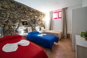 1 dormitorio con 2 camas y pared de piedra en PANORAMIC GREEN VALLEY, en Sulzano