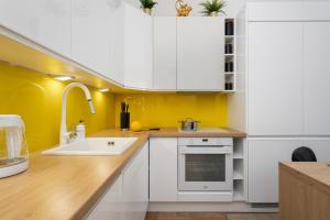 a kitchen with white cabinets and a yellow wall at Marina Na Grobli Studio Apartments by Renters in Wrocław