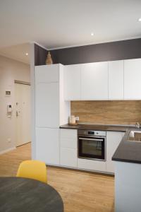 uma cozinha com armários brancos, uma mesa e cadeiras amarelas em Regina Apartment em Pescara