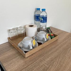 - un plateau en bois avec des tasses et des bouteilles d'eau sur une table dans l'établissement Ivory House Sriracha, à Si Racha